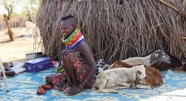 Kenianerin sitzt mit ihrem Vieh auf dem Boden