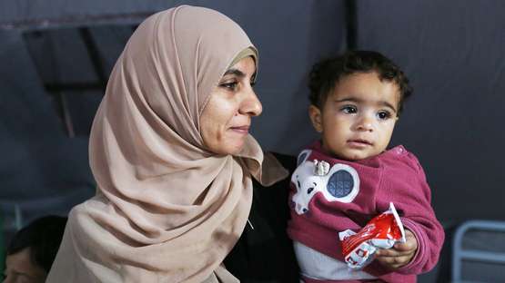 Eine Frau mit einem Kleinkind auf dem Arm, Gaza