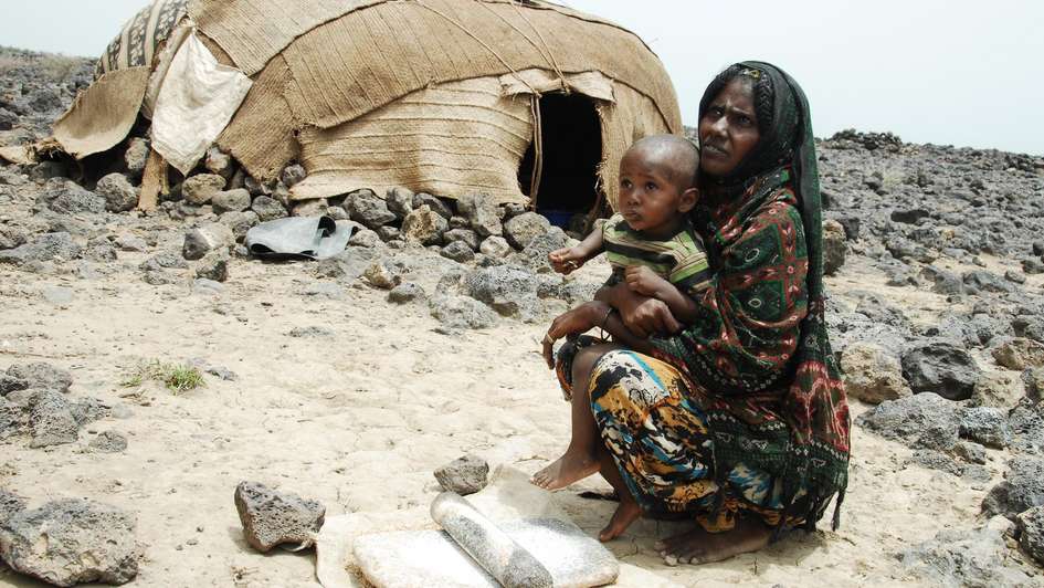 A mother with her child in front of their tent.