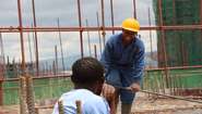 Zwei Männer im SkillUp!-Projekt sprechen auf einer Baustelle in Kenia miteinander.
