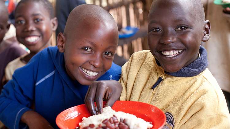 Kinder mit einem gefüllten Teller bei einer Schulspeisung im Dorf Vumbi in der Provinz Kirundo, Uganda.