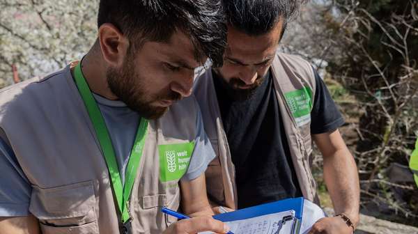 Zwei Männer prüfen eine Liste auf einem Klemmbrett. Vorausschauendes humanitäres Handeln ist mit viel Planung verbunden.