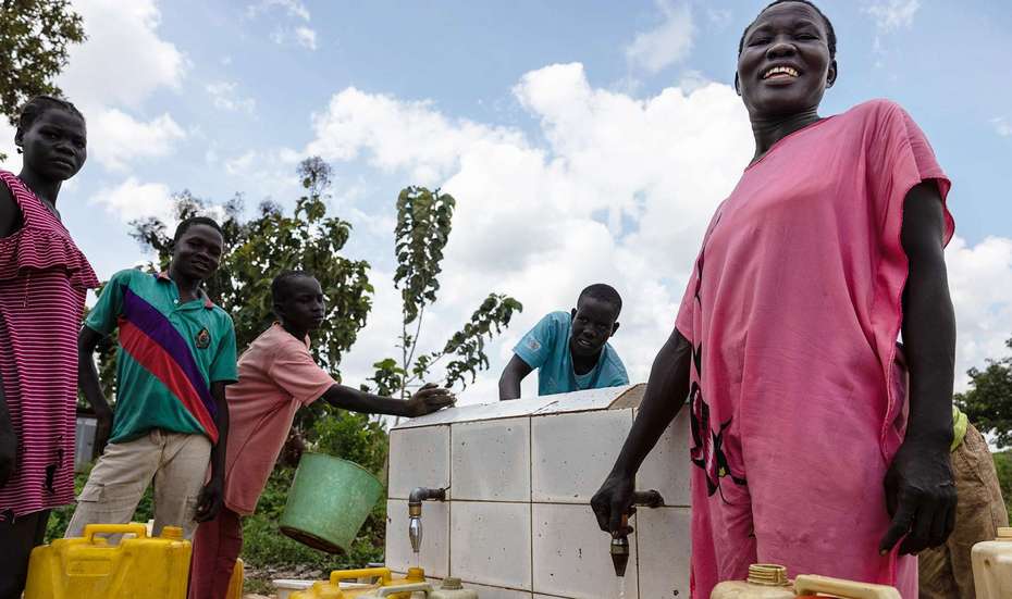 Menschen in Uganda stehen um eine Wasserzapfanlage