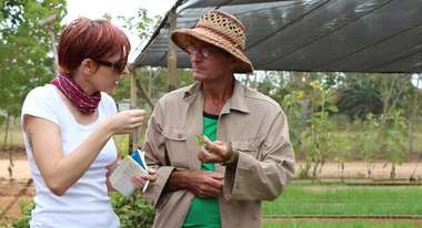 Ein Bauer zeigt Referentin Katharina Phillips seine Beete