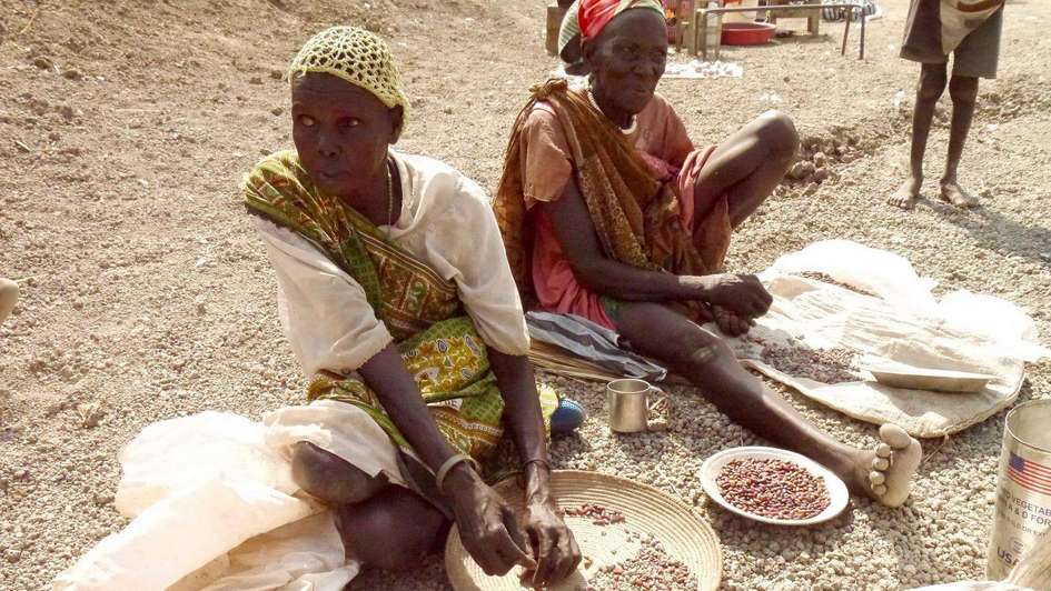 Women in South Sudan sitting on the floor sorting food.