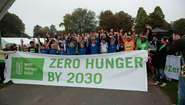 Gruppenaufnahme: Teilnehmer halten einen Banner mit der Aufschrift "Zero Hunger By 2030"