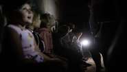 Ukrainische Kinder in einem Bunker, im Hintergrund leuchtet eine Taschenlampe