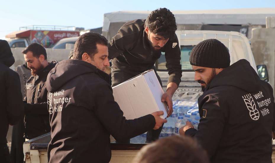 Nach dem Erdbeben in der Türkei und Nordwestsyrien: Drei Mitarbeiter der Welthungerhilfe laden Hilfsgüter in Afrin von einem Lkw ab