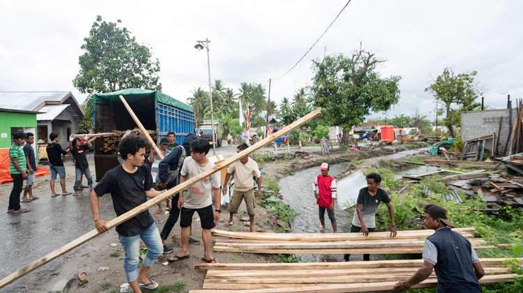 Mehrere Männer laden Holzlatten von einem Lastwagen.