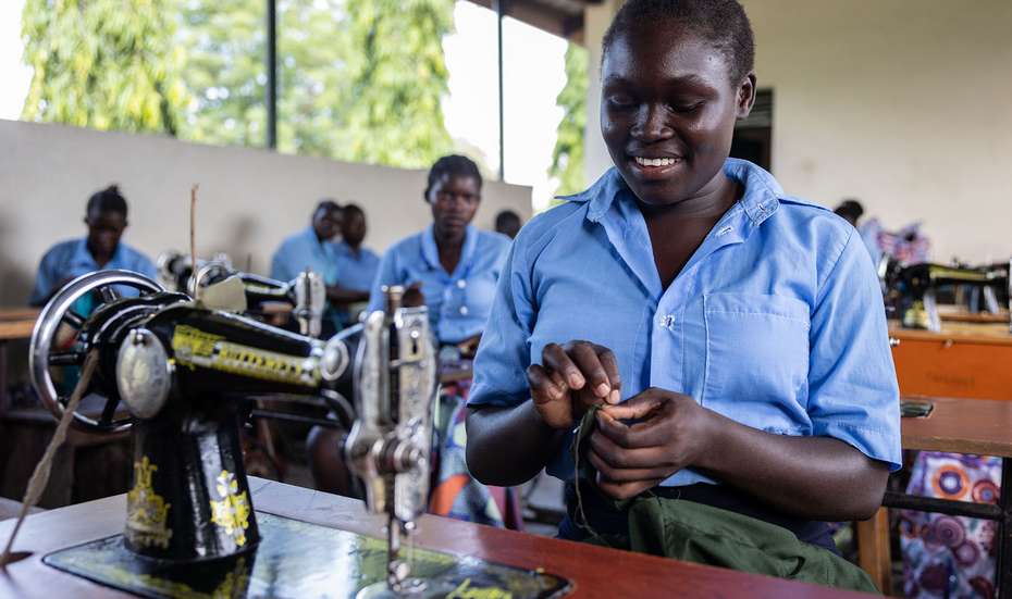 Junge Frau aus Uganda lernt in einer Schule das Nähen an einer Nähmaschine