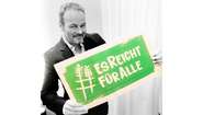 Schauspieler Till Demtrøder hält ein Schild mit dem Welthungerhilfe-Hashtag #EsReichtFürAlle.