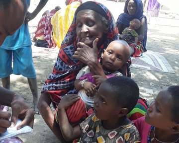 Eine Frau mit Kindern, die wegen der Überschwemmungen in Afrika auf Spenden angewiesen ist.