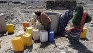 Menschen holen mit Kanistern Wasser vom Brunnen