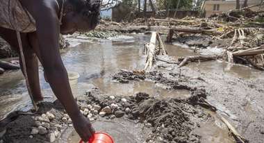 Wetterextreme treffen oft die Ärmsten - Eine Frau schöpft Wasser nach Hurrikan Mathew in Haiti.