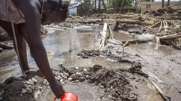 Eine Frau in Haiti schöpft nach Hurrikan Matthew verschmutztes Wasser
