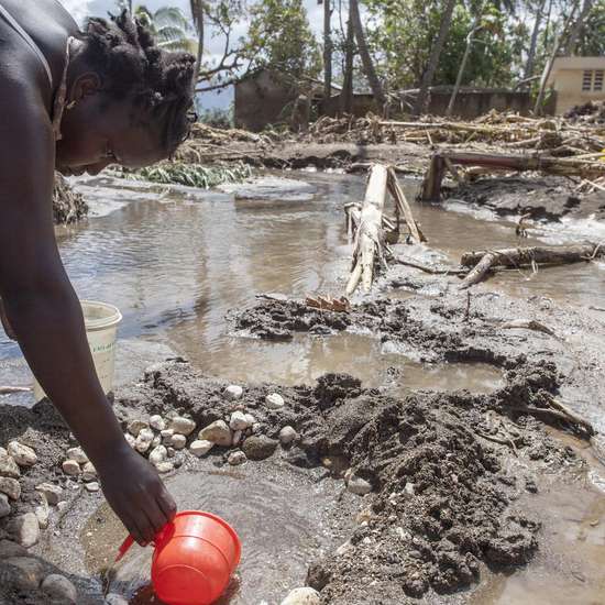 Wetterextreme treffen oft die Ärmsten - Eine Frau schöpft Wasser nach Hurrikan Mathew in Haiti.