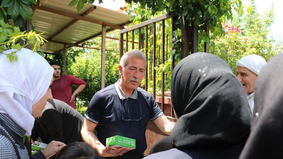 Ein Welthungerhilfe-Mitarbeiter verteilt Datteln an Flüchtlinge aus Syrien.