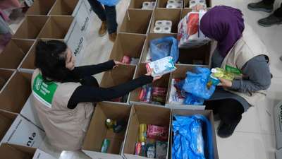 Zwei Frauen packen Hilfsgüter in Kartons.