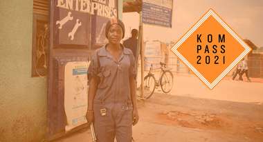 Ausbildungsprogramm "Skill up!" in Uganda. Eine Frau Sie trägt einen blauen Overall und hält Werkzeuge in der Hand. Rechts ist das "Kompass 2021" Logo.