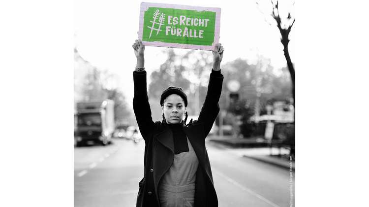 Schauspielerin Jane Chirwa hält ein Schild mit dem Welthungerhilfe-Hashtag #EsReichtFürAlle über den Kopf.