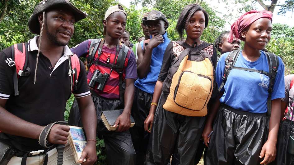 Green Colleges in Uganda: Ausbilder Arthur Alinaiture und seine Student/innen Fünf Menschen stehen im Wald.