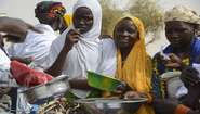 Junge Frauen im Niger halten Schalen und Töpfe.