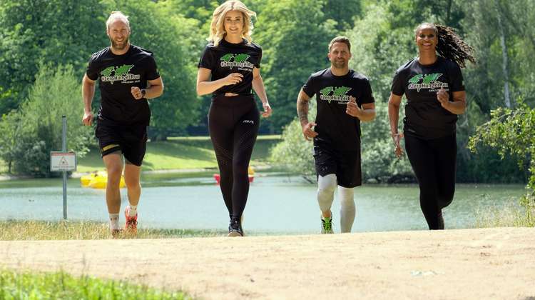 Arne Greskowiak, Nina Ensmann, Florian Ambrosius und Liz Baffoe laufen nebeneinander vor einem See. Sie alle tragen schwarze ZeroHungerRun T-Shirts.