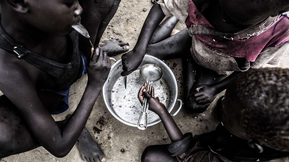 Hungersnöte verhindern. Bild: Dorfkinder in Bothoni, Südsudan essen ein Fischgericht.