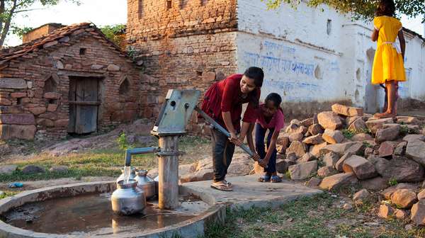 Zugang zu Wasser - Mädchen pumpen Wasser aus einer Handpumpe.