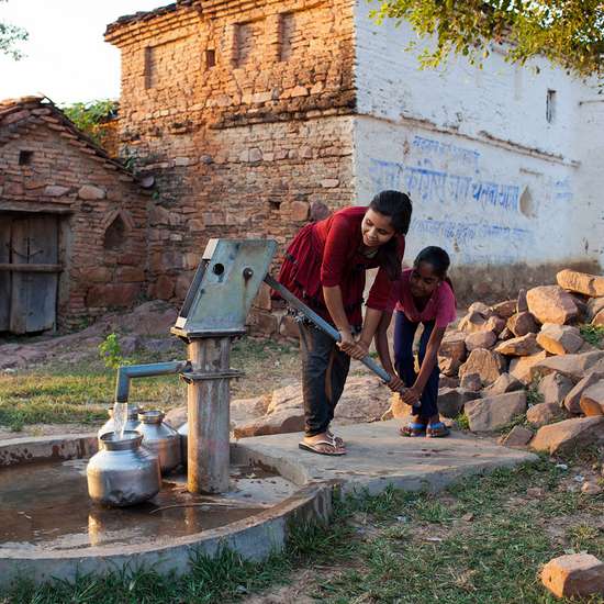Jetzt spenden für Wasser und Hygiene! Bild: Mädchen pumpen Wasser aus einer Handpumpe.