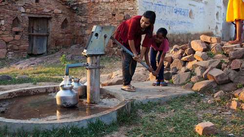 Mädchen pumpen Wasser aus einer Handpumpe
