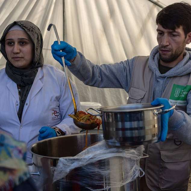 Eine Frau und ein Mann stehen in einem Zelt und verteilen Mahlzeiten.