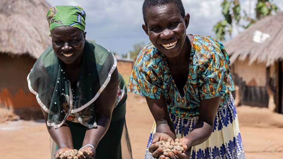 Zwei Frauen zeigen ihre Erdnuss-Ernte.