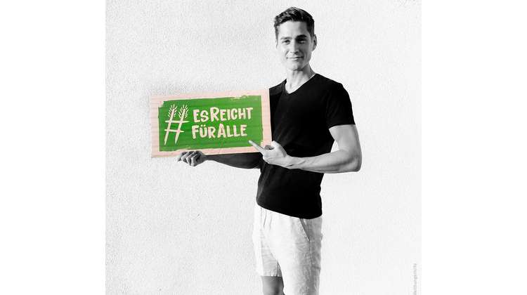 Schauspieler Timothy Boldt hält ein Schild mit dem Welthungerhilfe-Hashtag #EsReichtFürAlle.