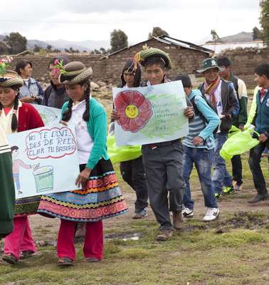 Menschen in bunter, traditoneller Kleidung sammeln beim Umwelttag in Peru gemeinsam Müll.