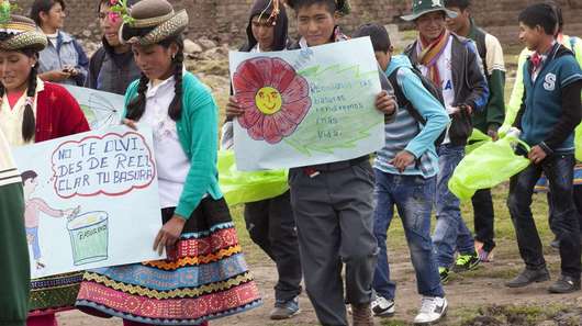 Menschen in bunter, traditoneller Kleidung sammeln beim Umwelttag in Peru gemeinsam Müll.