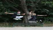 Florian Ambrosius und Nina Ensmann springen in die Luft. Im Hintergrund sind ein Baum und eine Parkbank zu sehen.