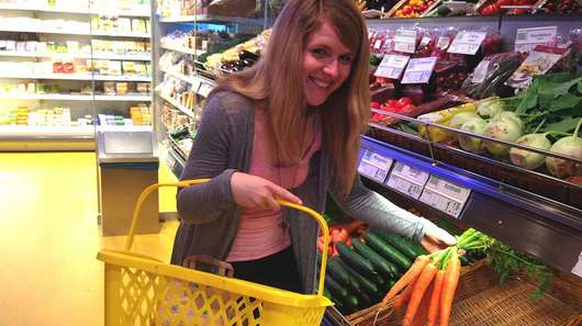 Janin kauft im Supermarkt ein und trägt dazu einen Einkaufskorb.