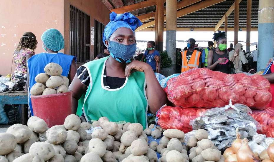Eine Frau mit Maske hinter ihrem Marktstand, Angola.