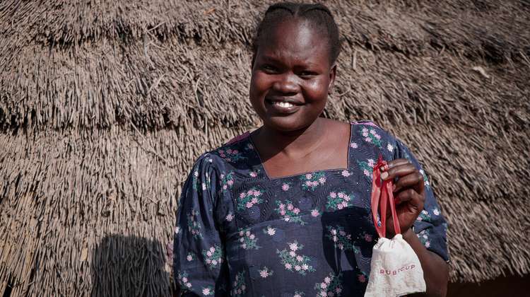 Eine junge Frau hält ein Säckchen mit einer Menstruationstasse in der Hand, Südsudan 2022. 