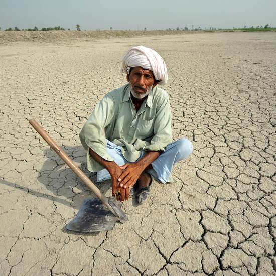 Ein Mann sitzt auf einem rissigen Boden, der die Folgen von Bodendegradation deutlich macht.