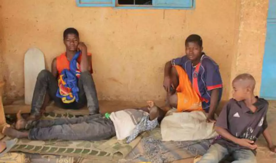Jugendliche sitzen vor einem Haus, Burkina Faso.