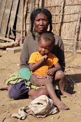 Eine Großmutter und ihre Enkelin in Madagaskar essen rohen Maniok