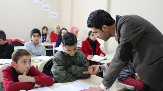 Hilfe für syrische Flüchtlinge. Bildbeschreibung: Ein Lehrer erklärt den Schülern etwas.