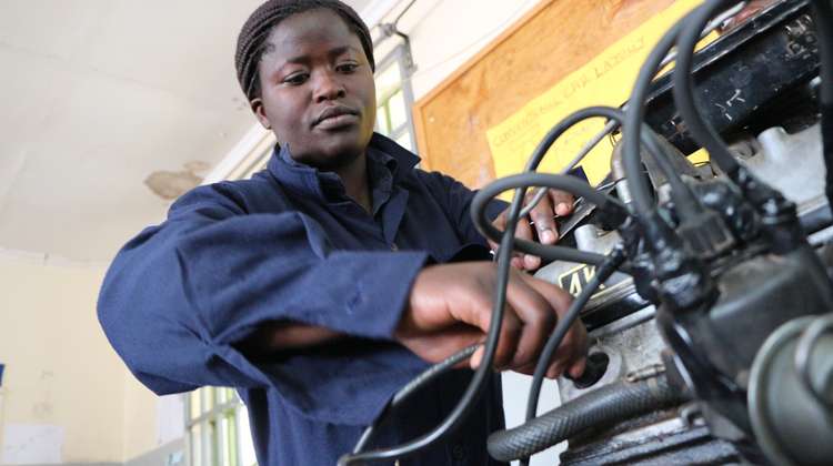 Weiterbildung mit Perspektive in Kenia: Emma war die erste Frau, die im Rahmen des Programms "Skill up!" eine Ausbildung zur Mechanikerin gemacht hat. Eine Frau in blauem Overall arbeitet an einem Motor.