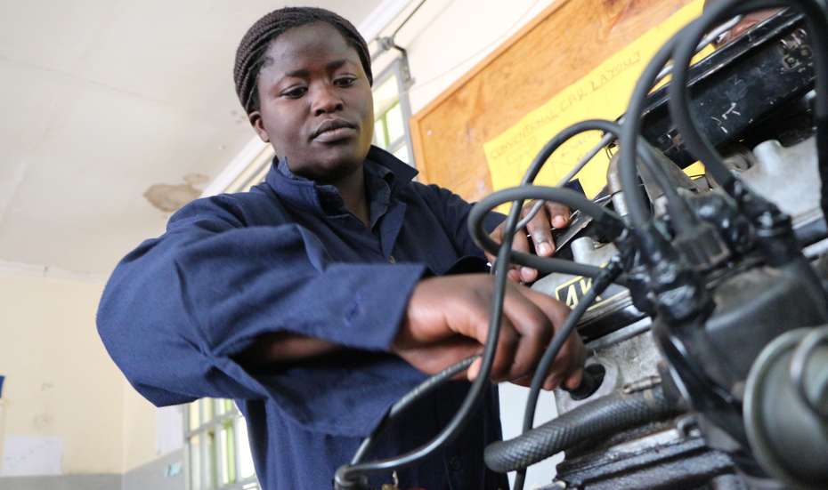 Weiterbildung mit Perspektive in Kenia: Emma war die erste Frau, die im Rahmen des Programms "Skill up!" eine Ausbildung zur Mechanikerin gemacht hat. Eine Frau in blauem Overall arbeitet an einem Motor.