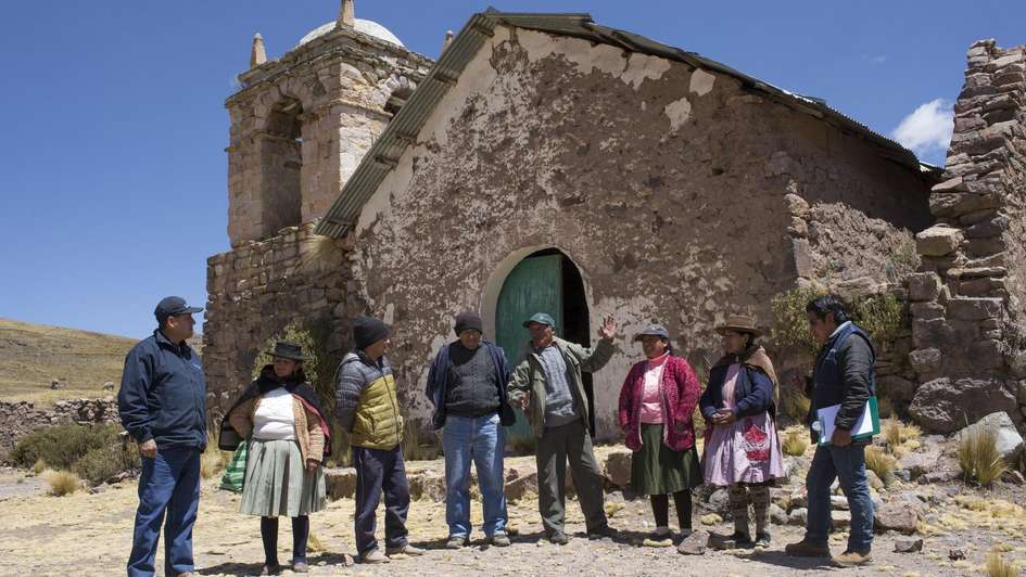 Dorfbewohner stehen vor einer Kirche.