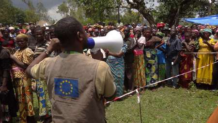 Ein Mann spricht durch ein Megaphon zu einer Menschenmenge in Katoto, Kongo