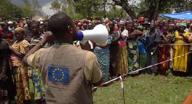 Ein Mann spricht durch ein Megaphon zu einer Menschenmenge in Katoto, Kongo