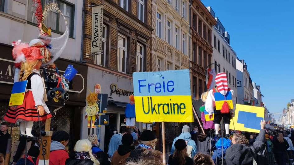 Mehrere Menschen halten Schilder in die Höhe - auf einem Schild steht "Freie Ukraine".